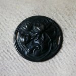 Medalhão de lírio de água em relevo de metal preto com laços laterais 