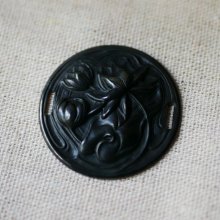 Medalhão de lírio de água em relevo de metal preto com laços laterais 
