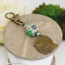 chaveiro medalha duo de pássaros cor bronze e pérola floral trabalhada motivo floral verde e vinho leesmulticolour