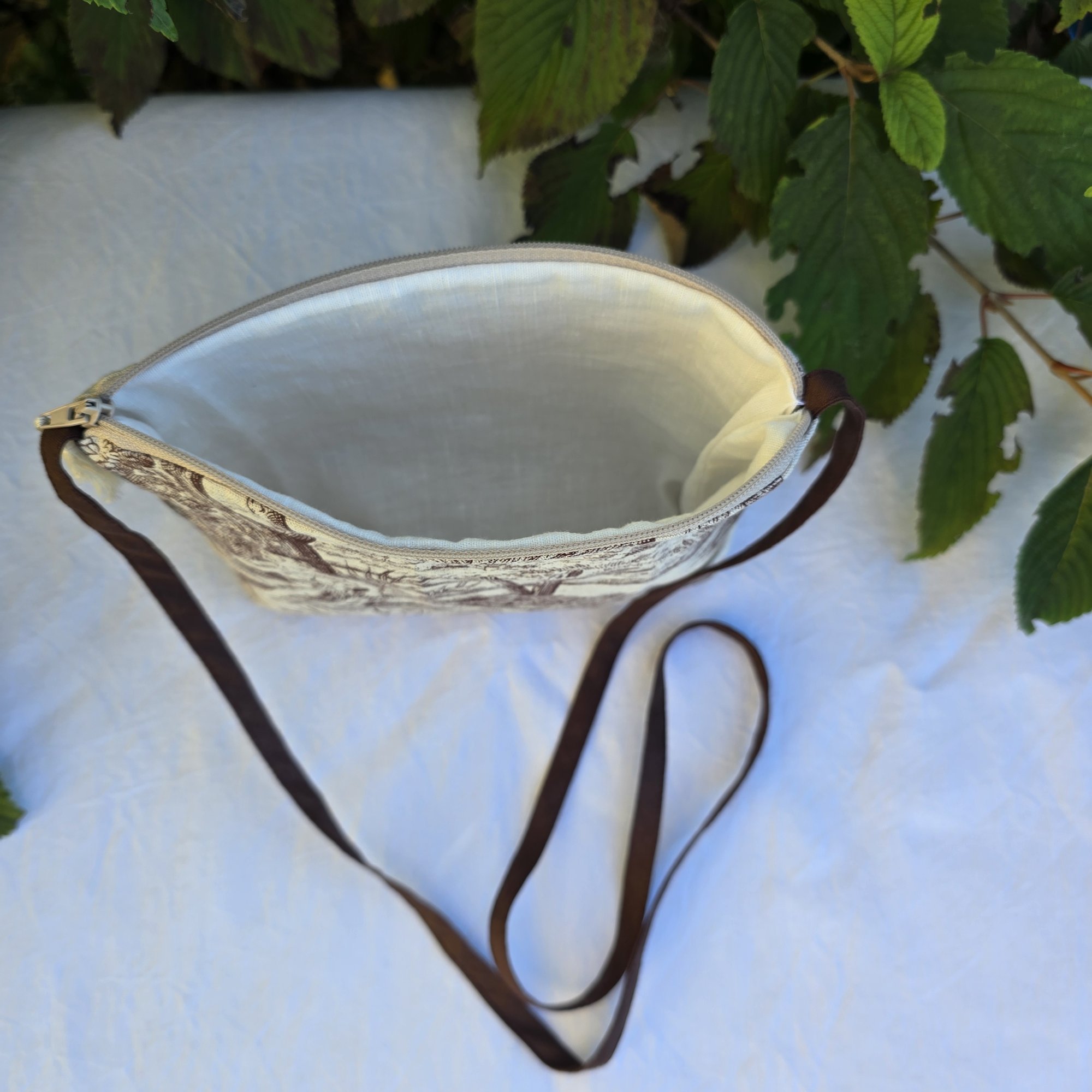 Pochette avec bandouli&egrave;re en tissu toile de Jouy marron et beige agr&eacute;ment&eacute;e d'un pompon