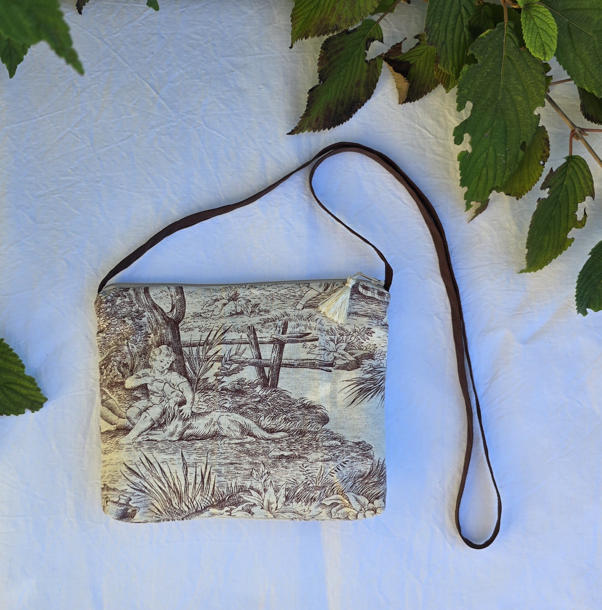 Pochette avec bandouli&egrave;re en tissu toile de Jouy marron et beige agr&eacute;ment&eacute;e d'un pompon