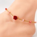 Tornozeleira de coral com rosa vermelha sobre corrente de aço dourada