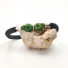 Crânio duplo e bracelete de ossos cruzados com pedras verdes sobre corda preta