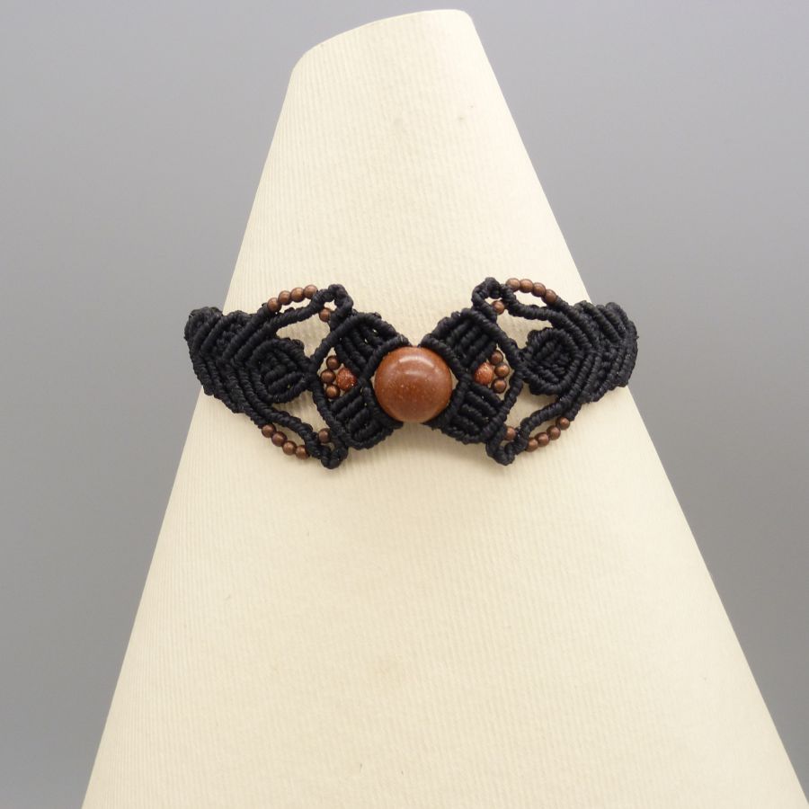 Pulseira micromacramé preta com uma conta central de "pedra sol"