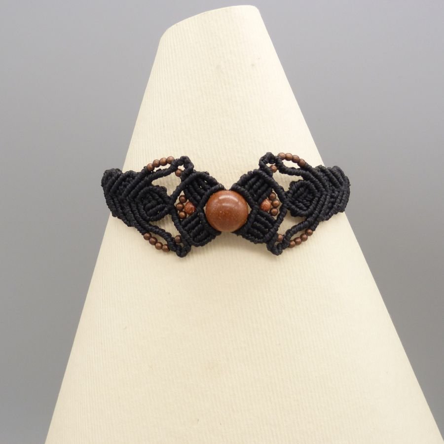 Pulseira micromacramé preta com uma conta central de "pedra sol"