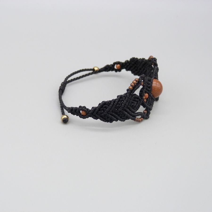 Pulseira micromacramé preta com uma conta central de "pedra sol"