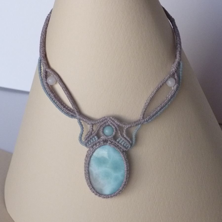 Colar em micro-macramé cinzento-acinzentado/azulado fosco com uma pedra preciosa natural em tons suaves de branco e azul claro como peça central.