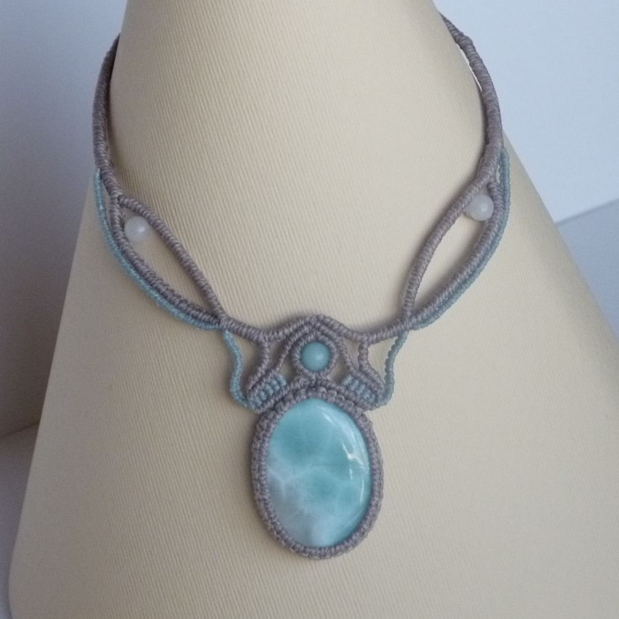 Colar em micro-macramé cinzento-acinzentado/azulado fosco com uma pedra preciosa natural em tons suaves de branco e azul claro como peça central.
