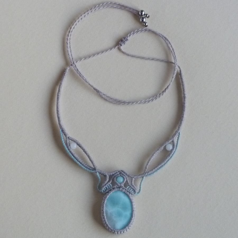 Colar em micro-macramé cinzento-acinzentado/azulado fosco com uma pedra preciosa natural em tons suaves de branco e azul claro como peça central.