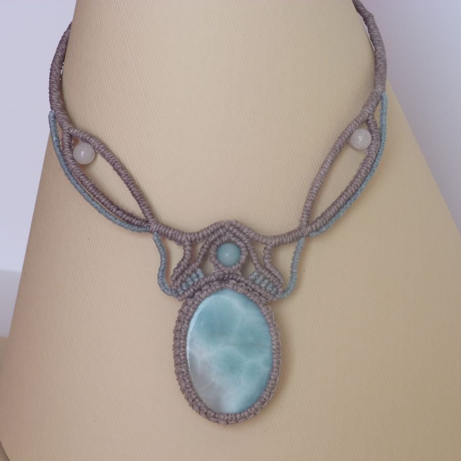 Colar em micro-macramé cinzento-acinzentado/azulado fosco com uma pedra preciosa natural em tons suaves de branco e azul claro como peça central.