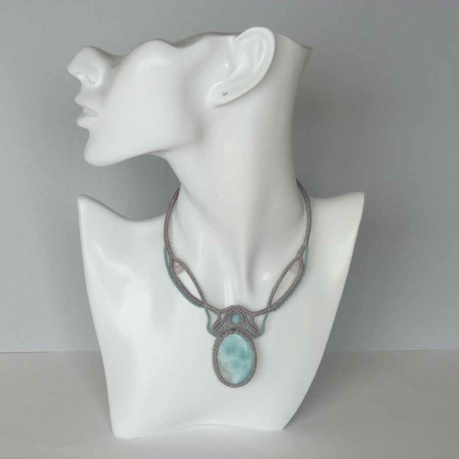 Colar em micro-macramé cinzento-acinzentado/azulado fosco com uma pedra preciosa natural em tons suaves de branco e azul claro como peça central.