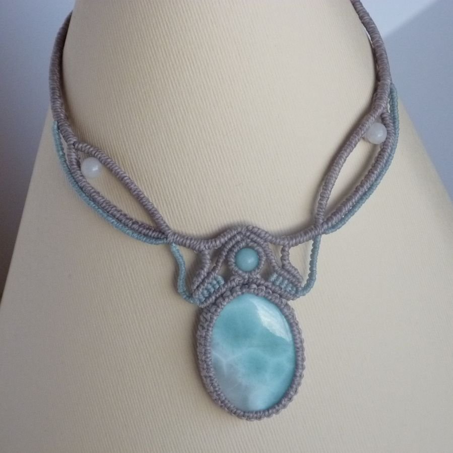 Colar em micro-macramé cinzento-acinzentado/azulado fosco com uma pedra preciosa natural em tons suaves de branco e azul claro como peça central.