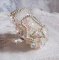 Anel Bouquet d'un Jour bordado com lírios de lucite, topos giratórios de cristal Swarovski, um cabochon perolado com missangas de prata e salmão