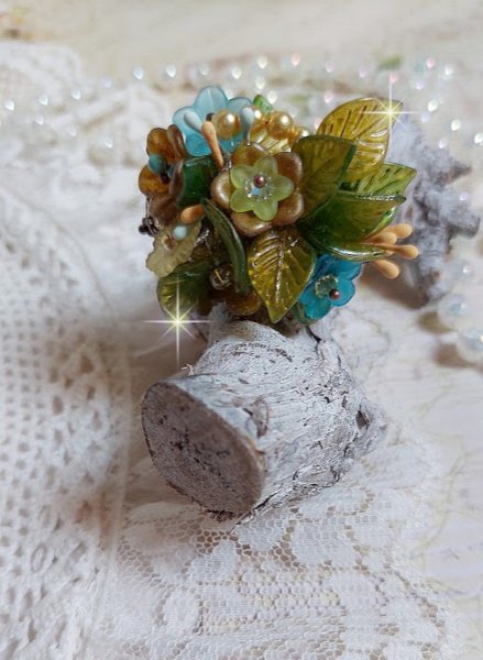 Bague C&eacute;zanne mont&eacute;e avec des petites fleurs lucites peintes &agrave; la main &agrave; laquelle s&rsquo;ajoute des feuilles, cristaux, perles, &eacute;tamines, grosses rocailles, perles nacr&eacute;es et m&eacute;tal sur une bague en Laiton