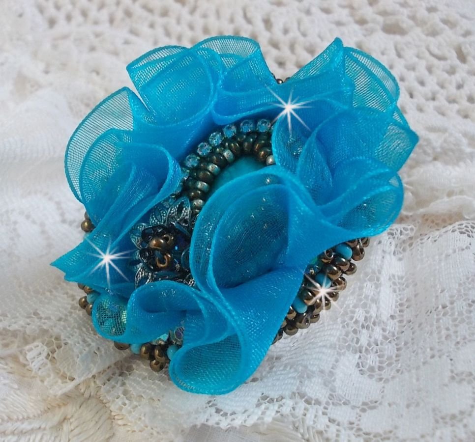 Ilycia Charming ring bordado com um cabochon facetado de resina azul turquesa e uma fita de organza
