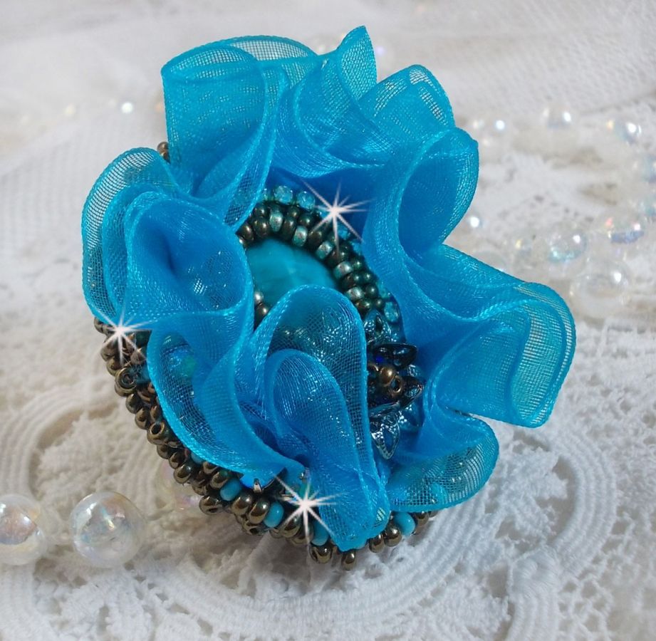 Ilycia Charming ring bordado com um cabochon facetado de resina azul turquesa e uma fita de organza
