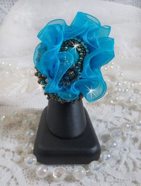 Ilycia Charming ring bordado com um cabochon facetado de resina azul turquesa e uma fita de organza