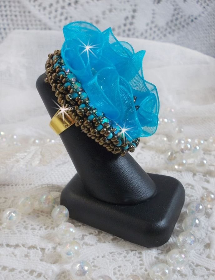 Ilycia Charming ring bordado com um cabochon facetado de resina azul turquesa e uma fita de organza