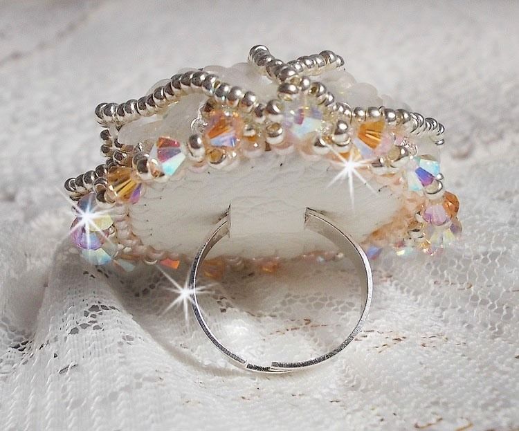 Anel Bouquet d'un Jour bordado com lírios de lucite, topos giratórios de cristal Swarovski, um cabochon perolado com missangas de prata e salmão