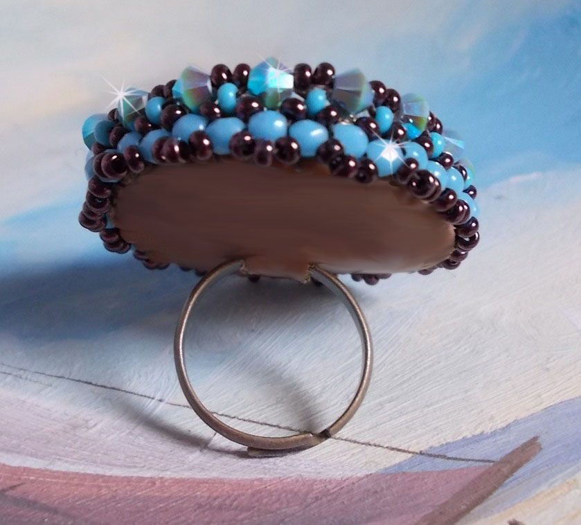 Anel naïade bordado com uma resina azul turquesa e cabochon de cristal, um belo jogo de luz.
