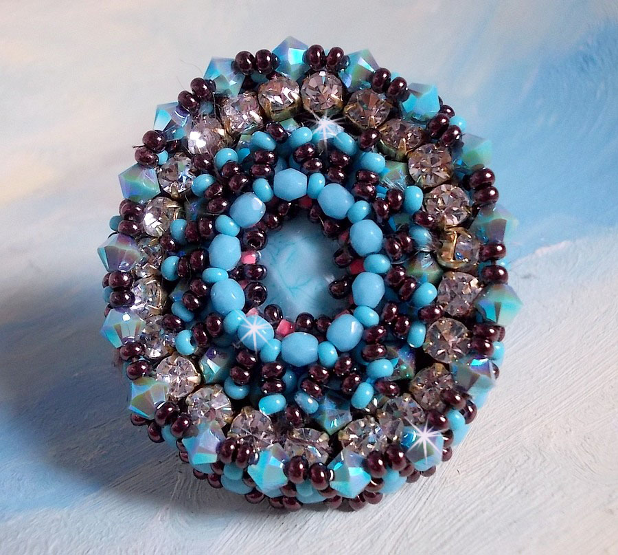 Anel naïade bordado com uma resina azul turquesa e cabochon de cristal, um belo jogo de luz.