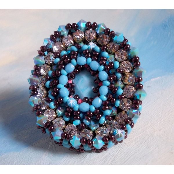 Anel na&iuml;ade bordado com uma resina azul turquesa e cabochon de cristal, um belo jogo de luz.