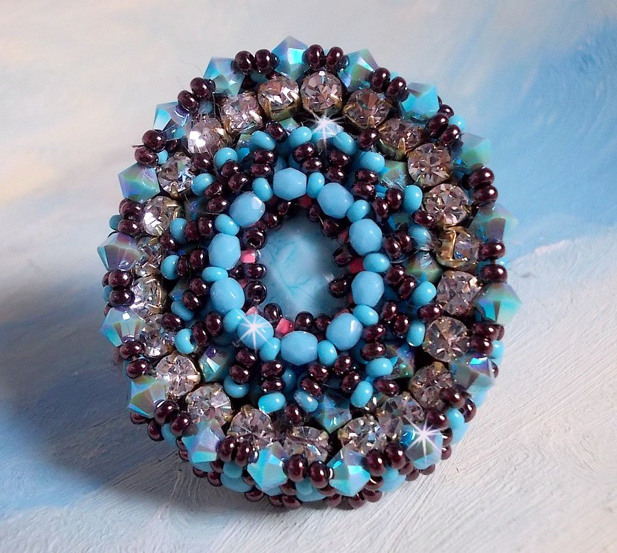 Anel naïade bordado com uma resina azul turquesa e cabochon de cristal, um belo jogo de luz.