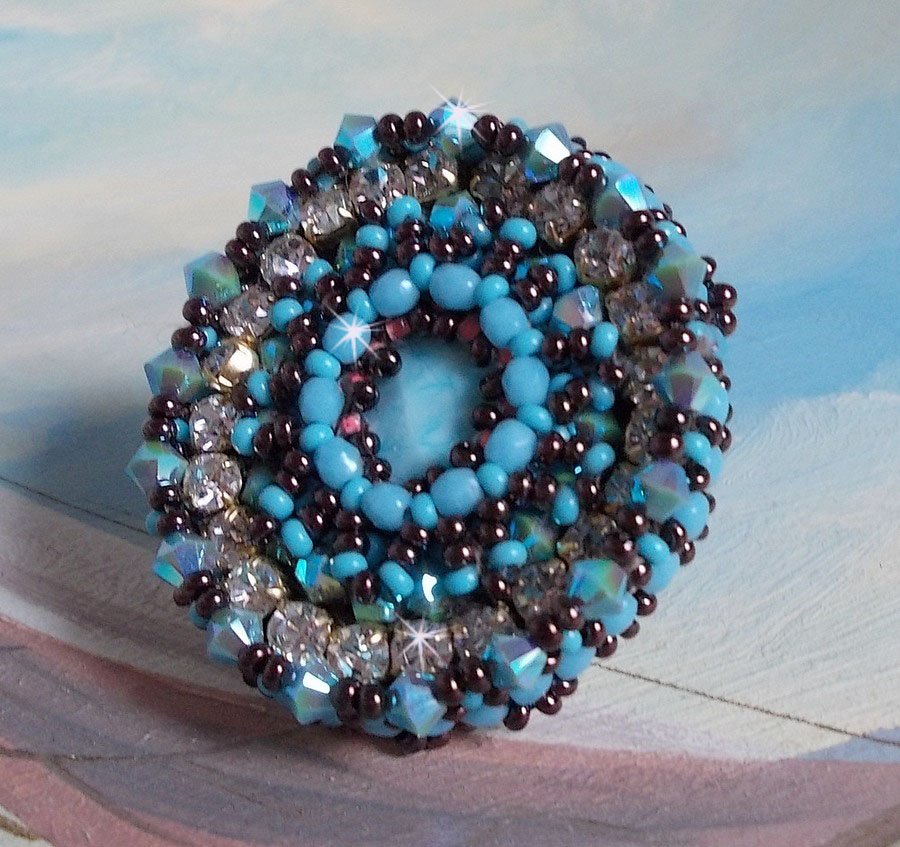 Anel naïade bordado com uma resina azul turquesa e cabochon de cristal, um belo jogo de luz.