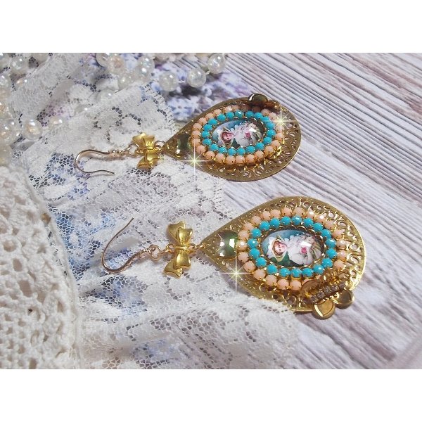 BO Mademoiselle Noellia avec des cabochons ovales repr&eacute;sentant une femme avec un chapeau et un n&oelig;ud blanc &agrave; laquelle s&rsquo;ajoute des cristaux, cha&icirc;nes strass P&ecirc;che et Turquoise sur crochets en plaqu&eacute; Or