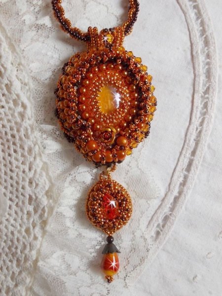 O colar pendente Lady in Orange &eacute; bordado com cristais Swarovski, missangas de sementes Miyuki e missangas m&aacute;gicas.