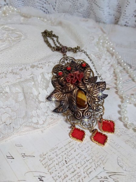 Pendentif M&eacute;lodie avec un cabochon &OElig;il de tigre orn&eacute; de perles en Jade Rouge vein&eacute; de Noir sur fleurs 5 p&eacute;tales et estampes mont&eacute;s sur une cha&icirc;ne bronze. Les pendants sont en r&eacute;sine &eacute;poxy Rouge