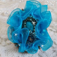 Ilycia Charming ring bordado com um cabochon facetado de resina azul turquesa e uma fita de organza