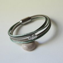 Pulseira multi-couro em tons de bege, verde pálido e perolado, decorada com uma pequena pena